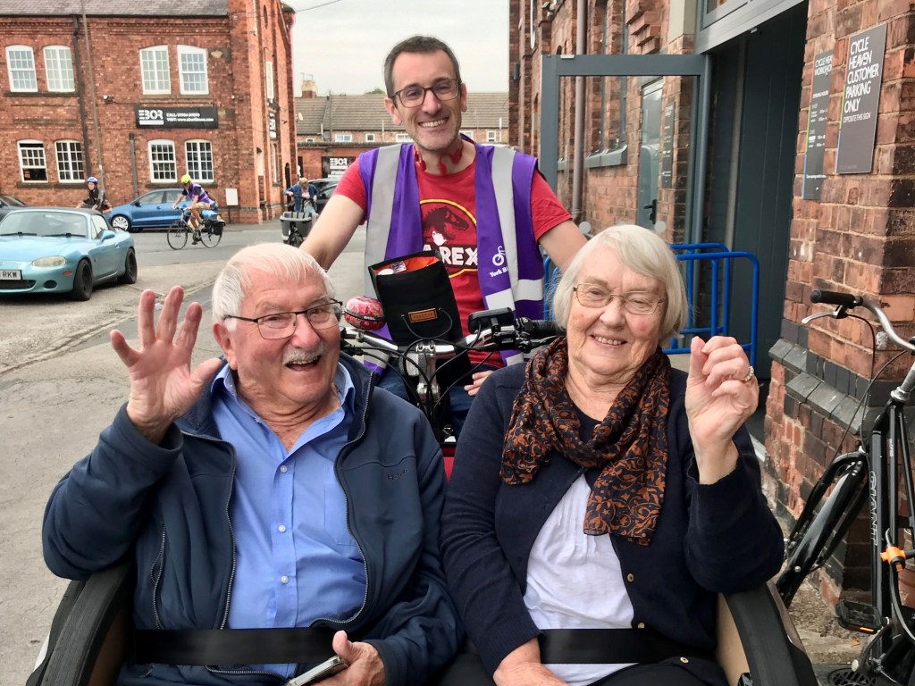 Two people in rickshaw smiling and waving