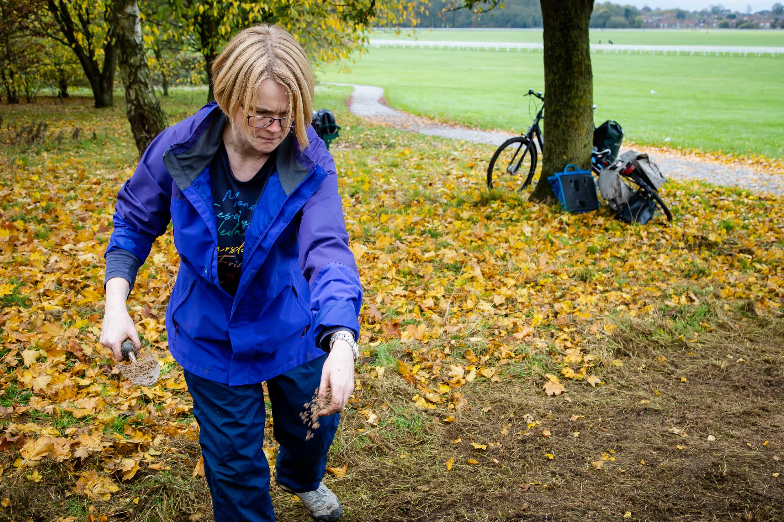 Woman scatters seed , ornage leaves behind