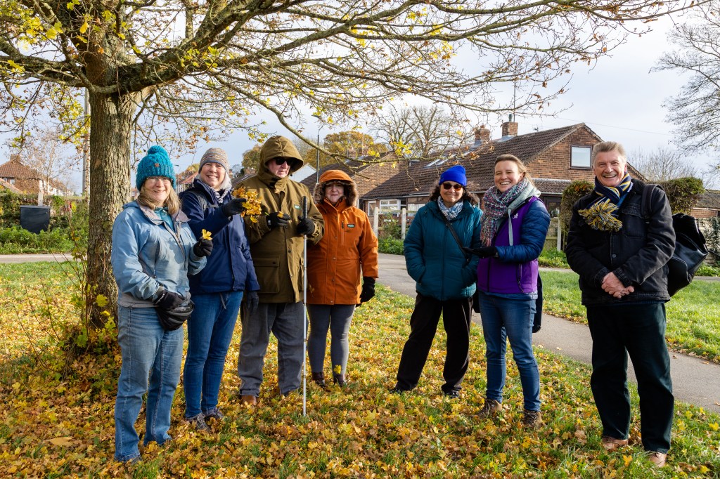 Group stand together under tree and smile
