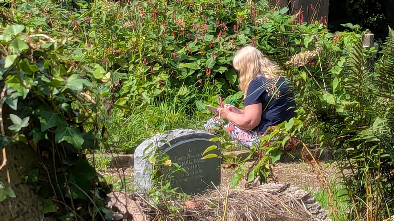 Woman sitting drawing amongst the flowers at York Cemetery